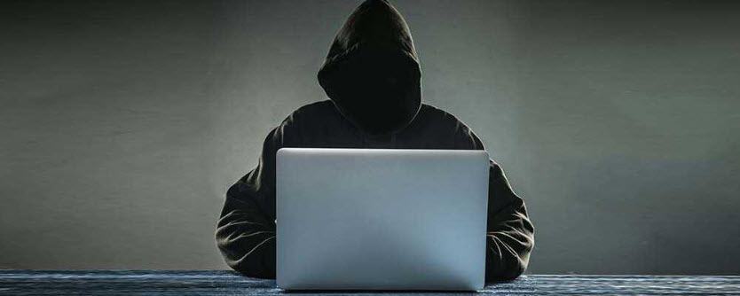 Person in hoodie behind laptop